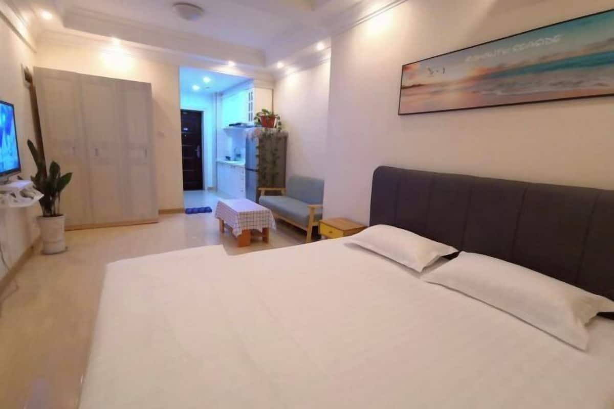 Une chambre d’hôtel avec un grand lit, une petite table, un canapé et un téléviseur sur le côté gauche.