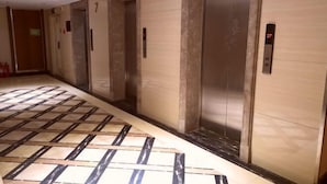 A corridor with elevators and a patterned floor. - Fashion Express Short-term Rental Apartment (Zhuanghe Xintiandi Huafu Branch) (Zhuanghe)