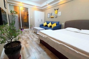 A bedroom with a bed, a sofa, a potted plant, and a sliding door leading to a balcony. - Fashion Express Short-term Rental Apartment (Zhuanghe Xintiandi Huafu Branch) (Zhuanghe)
