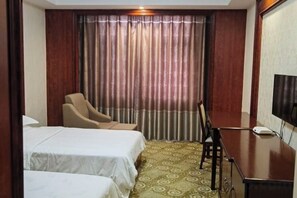 Habitación de hotel con dos camas, un escritorio, una silla y un televisor.