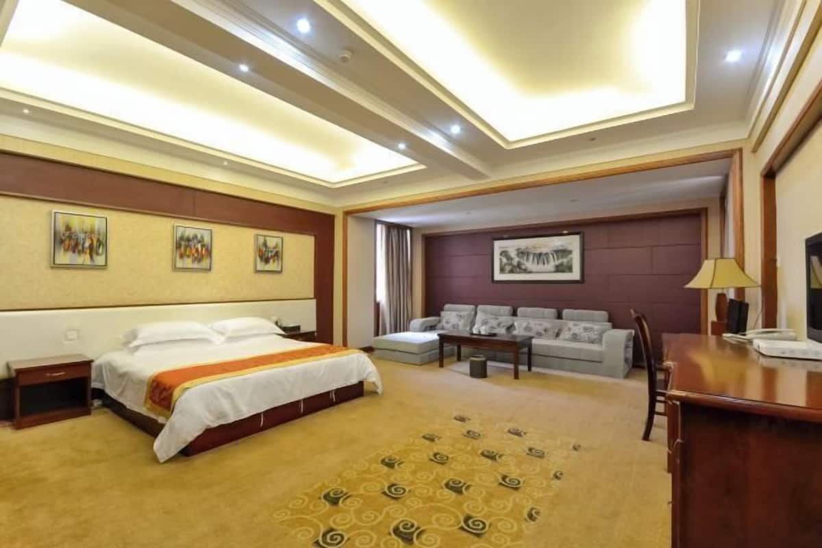 A hotel room with a bed, a sofa, a desk, and a chair.