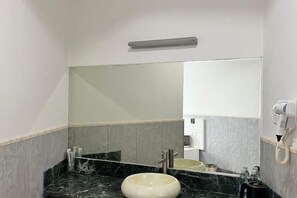 A bathroom with a marble sink, a large mirror, a hairdryer, and a towel rack.