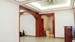 Un corridoio con una lampada a soffitto, porte in legno e pavimento piastrellato.