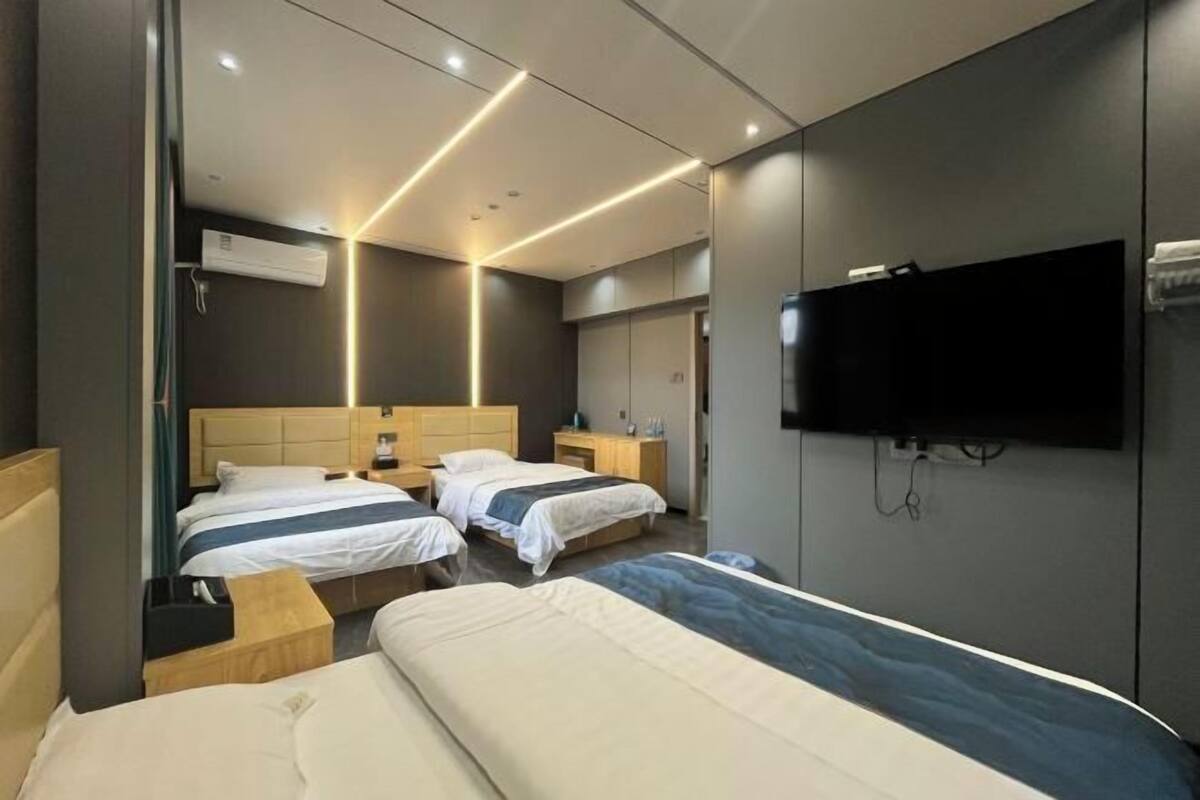 Ein modernes Hotelzimmer mit zwei Betten, einem flachbildfernseher an der Wand und einem Nachttisch mit Lampe.