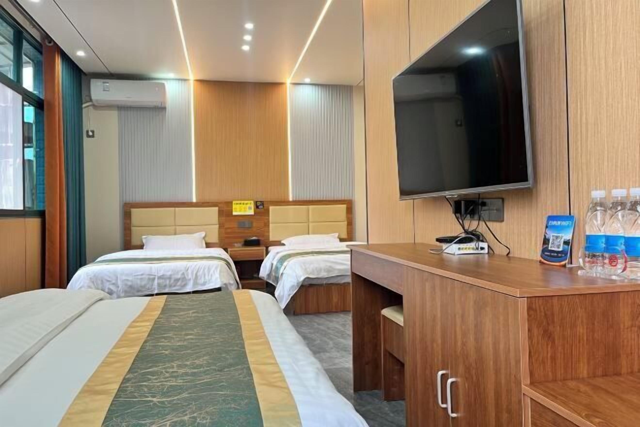 A hotel room with two beds, a desk, a television, and a minibar.