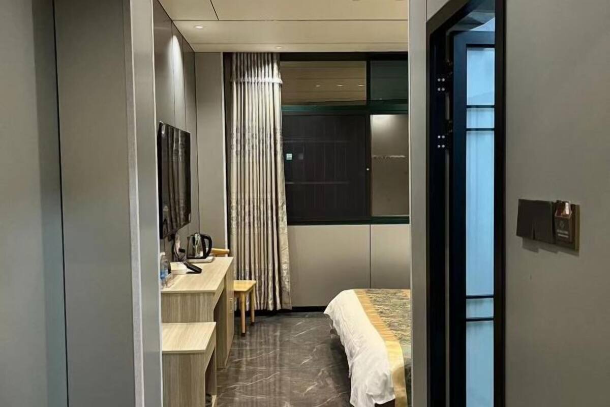 Ein modernes Hotelzimmer mit Bett, Schreibtisch mit Stuhl, einem kleinen Tisch, einem Vorhang und einem Fenster.