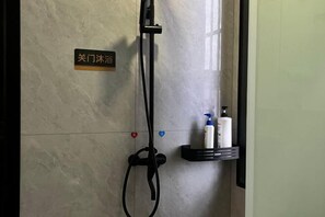A bathroom with a shower, a towel rack, and a shelf with toiletries.