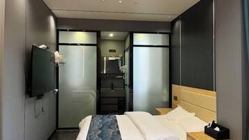 Une chambre d’hôtel moderne équipée d’un lit, d’une table de chevet et d’un téléviseur fixé au mur.