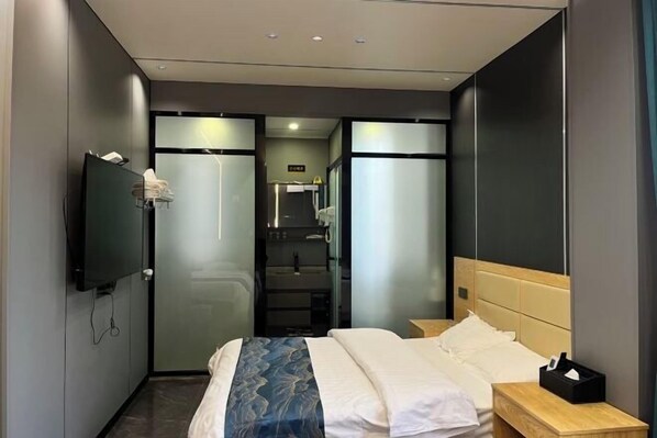 Una habitación de hotel moderna con cama, mesita de noche y televisor fijado a la pared.
