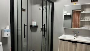 Un bagno moderno con cabina doccia in vetro, lavabo con specchio e servizi igienici.