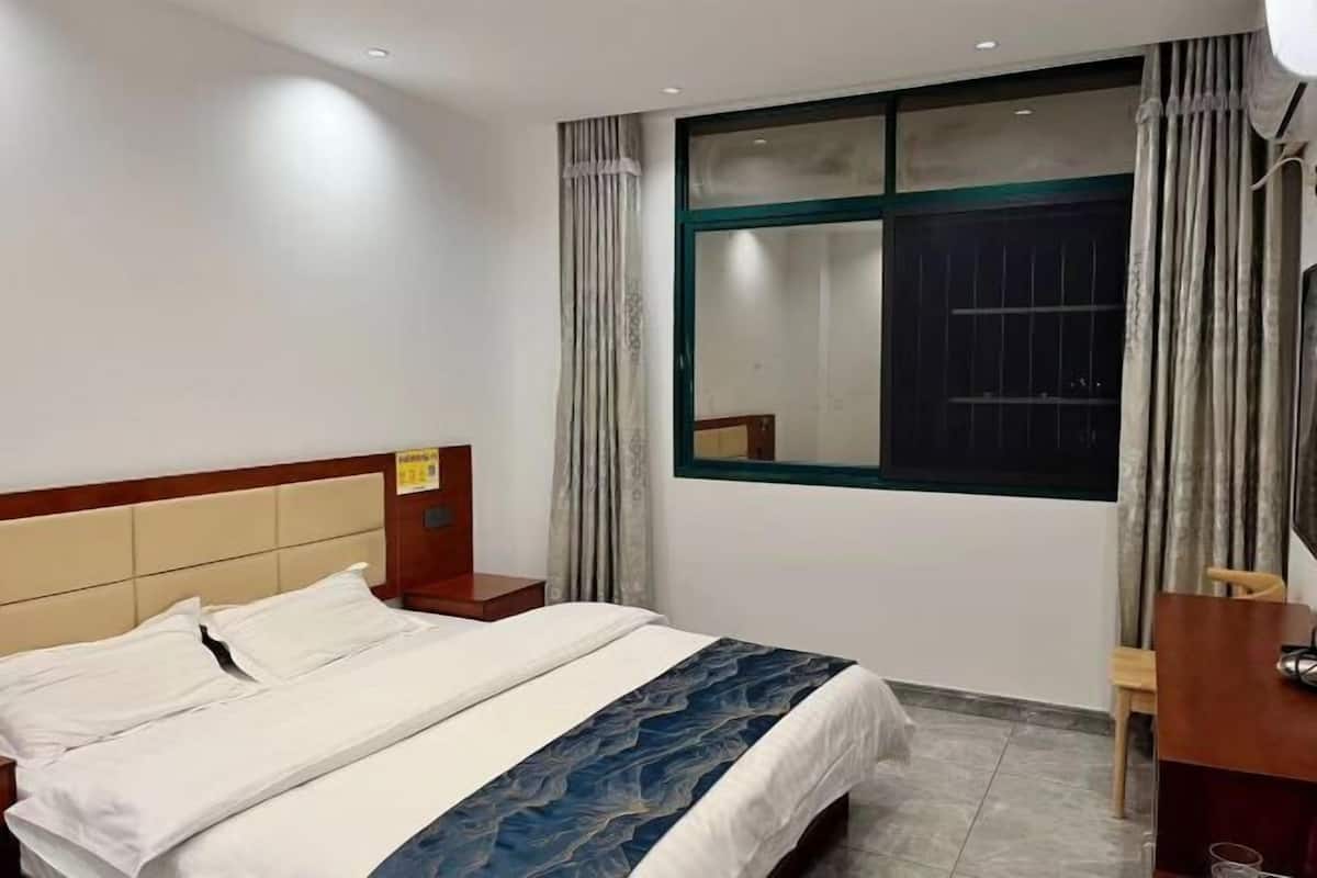 Ein Hotelzimmer mit Bett, Schreibtisch und einem Fenster mit Vorhängen.