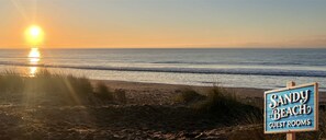 A beach scene with a sign for "Sandy Beach Guest Rooms". - Hoopers Sandy Beach Guest Rooms (Swansea)