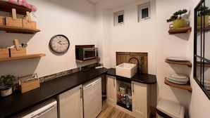 Een kleine keuken met een magnetron, spoelbak en houten planken.