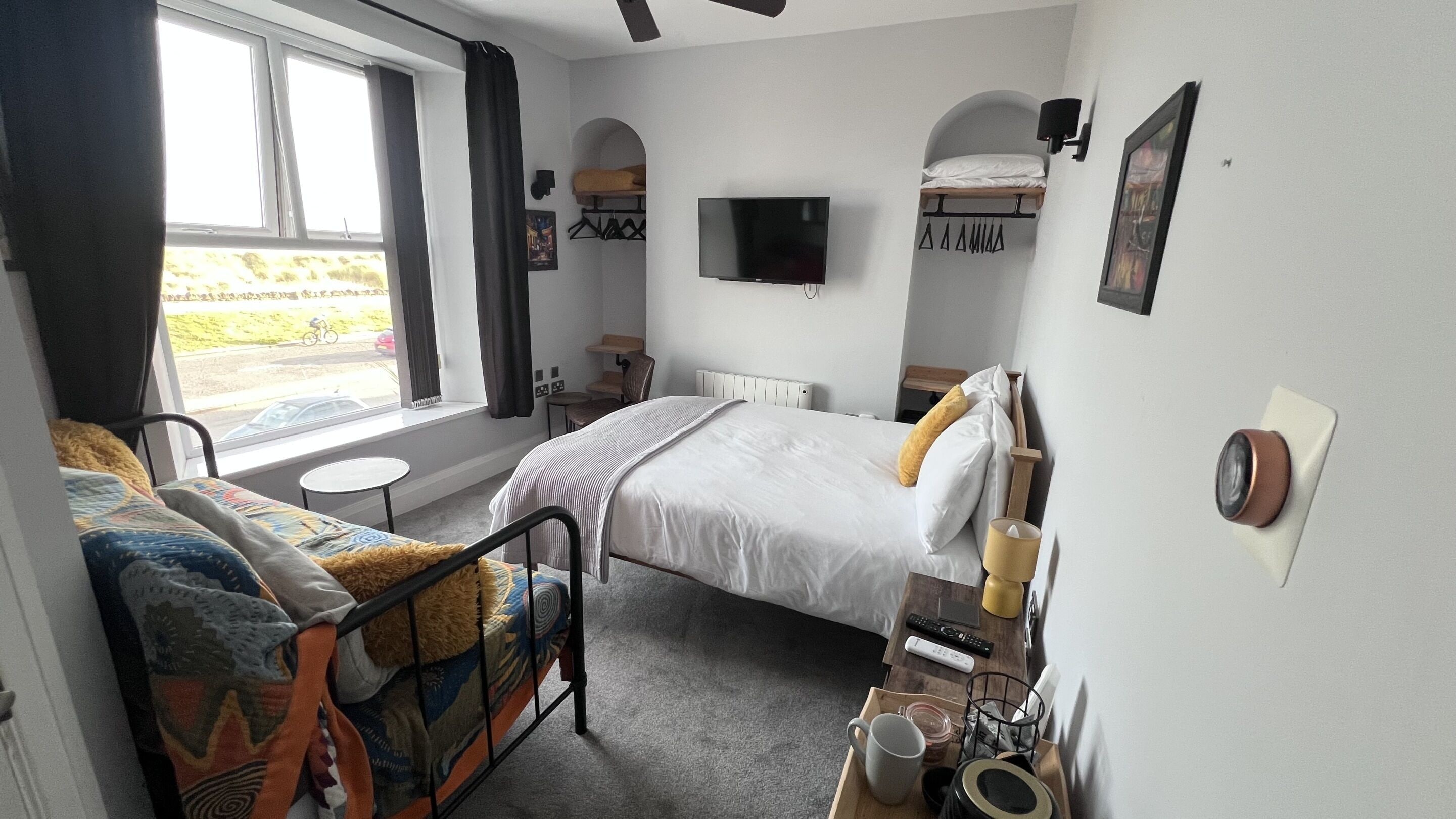 Une chambre d’hôtel de taille modeste, comprenant un lit, une petite table, une chaise, un téléviseur et une fenêtre avec des rideaux.
