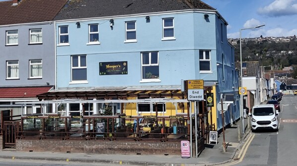 A two-story building with a blue facade, a ground-floor coffee bar, and a sign indicating the end of a street. - Hoopers Sandy Beach Guest Rooms (Swansea)