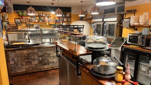 Een keuken met roestvrijstalen apparatuur, houten aanrecht en hangende pendellampen.