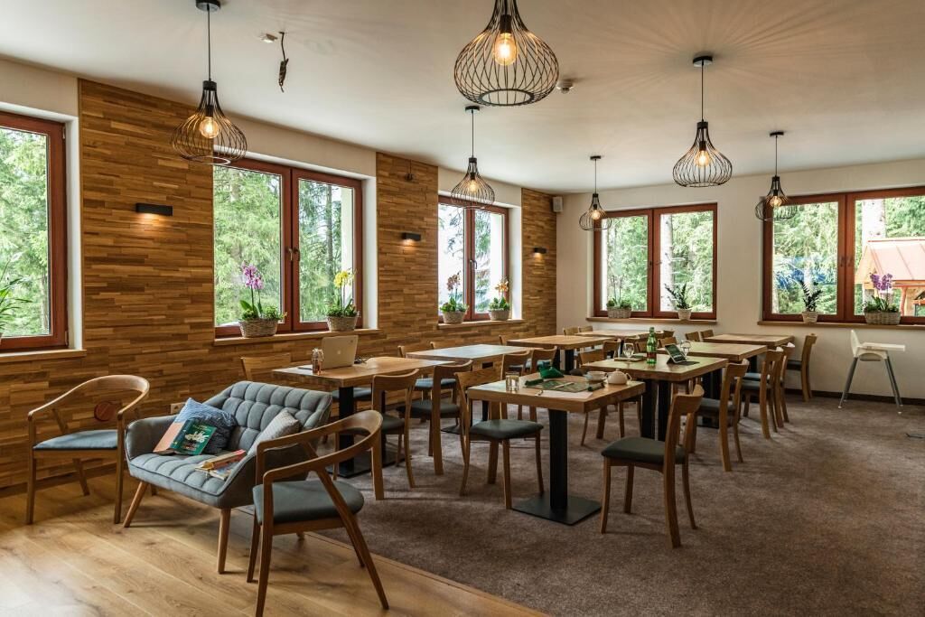 A spacious dining area with wooden walls, large windows, and hanging pendant lights.