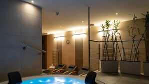 Un espace spa moderne doté d’un jacuzzi, de chaises longues et de plantes de bambou en pot.