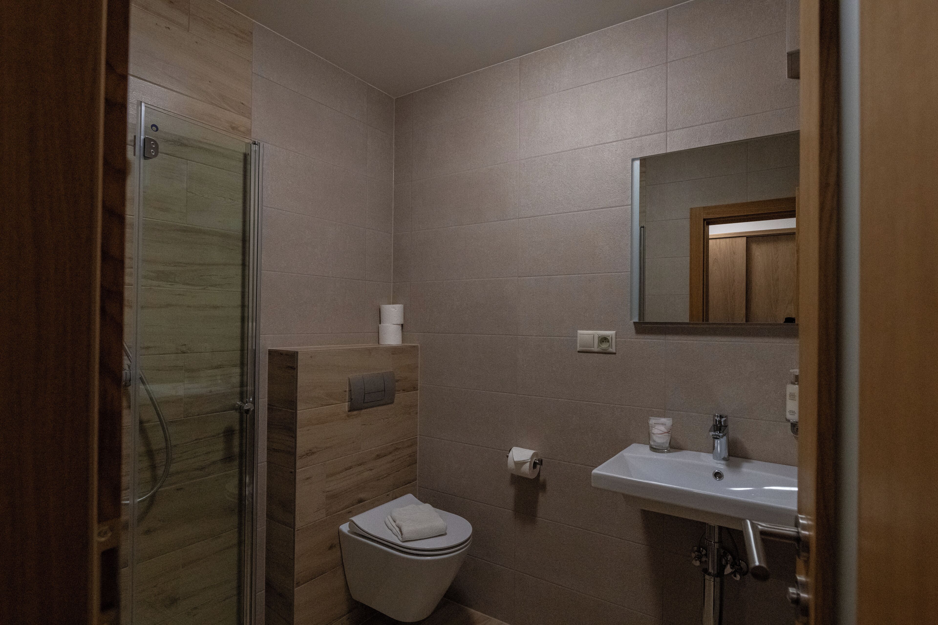Une salle de bain moderne avec une douche à parois de verre, des toilettes et un lavabo surmonté d’un miroir.