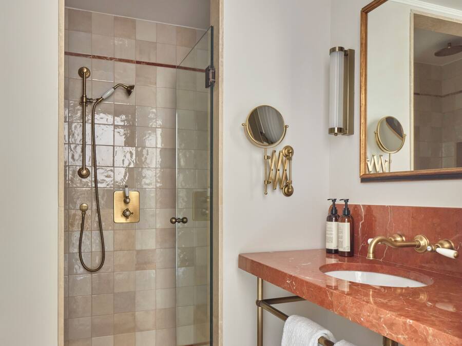A bathroom with a glass-enclosed shower, a marble sink, and a large mirror.