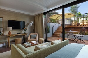 Una sala de estar moderna con un sofá, una mesa de centro y una televisión. Hay una escalera que conduce a un patio exterior con una mesa y sillas.