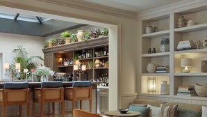 A modern kitchen with a bar area, wooden chairs, and a sofa with cushions. -  Miiro Borneta (Barcelona)