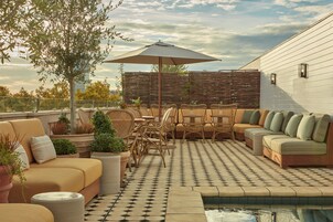 Un patio al aire libre con piscina, zona de estar y plantas en macetas.