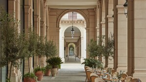 A long corridor with a central archway, flanked by potted plants and wicker furniture. -  Miiro Borneta (Barcelona)