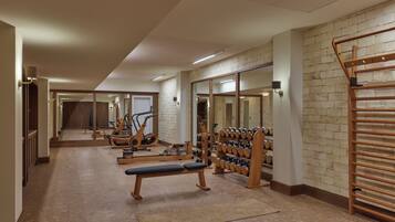 Ein Fitnessraum mit Trainingsgeräten, einer Bank und einem Hantelgestell.
