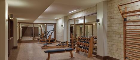 Uma academia com equipamentos de ginástica, um banco e uma barra de halteres.