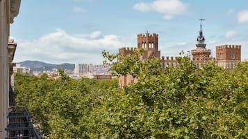 Vista de un edificio histórico con torres y una torre con aguja, rodeado de vegetación.