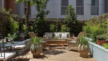 Un patio con mobiliario de mimbre, una mesa redonda y plantas en macetas.