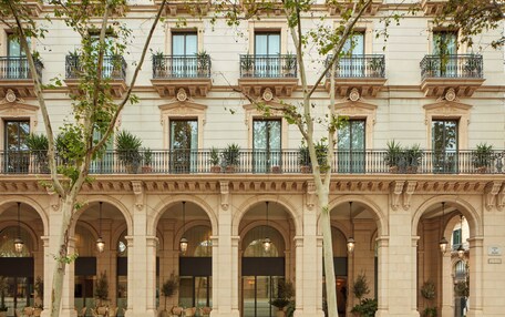 A historic building with multiple balconies, large arched windows, and outdoor seating areas.