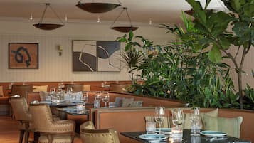 En restaurang med avskilda bås och bord, vissa med tomma tallrikar och glas.