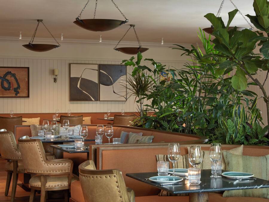En restaurang med avskilda bås och bord, vissa med tomma tallrikar och glas.