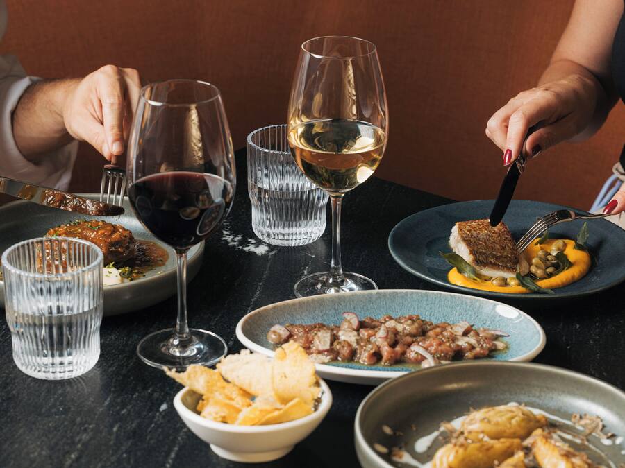 A dining table with various dishes, glasses of wine, and utensils.