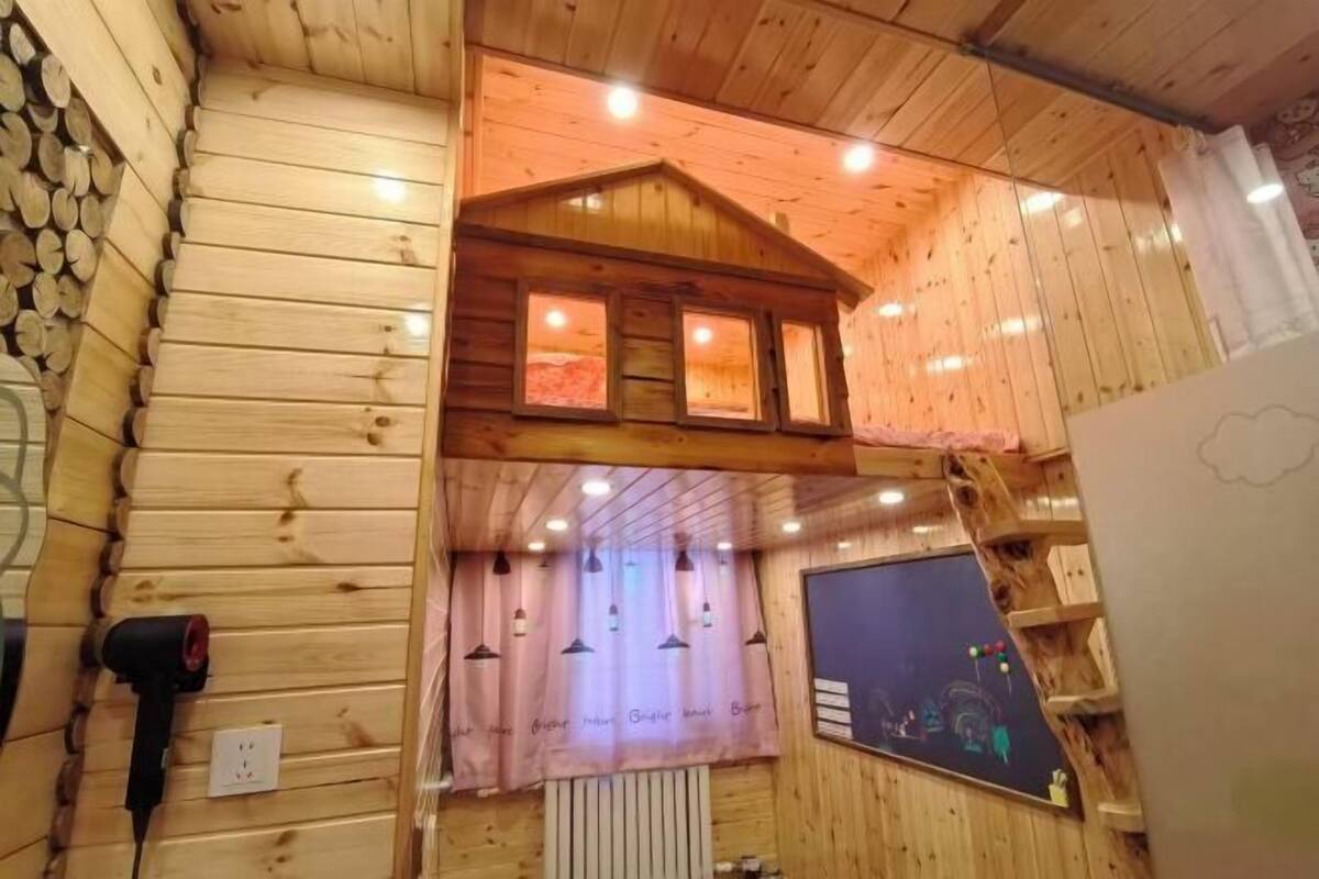 Ein Holzhütten-Innenraum mit Schlafkoje, einem Fenster mit Vorhängen und einem an der Wand montierten Heizkörper.