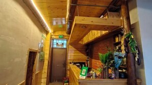 A wooden interior with a staircase, a door, and a sign with text. - Mohe Arctic Village Time Travel Youth Hostel (Mohe)