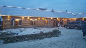 A log cabin with a metal roof, a covered porch, and a paved driveway. - Mohe Arctic Village Time Travel Youth Hostel (Mohe)