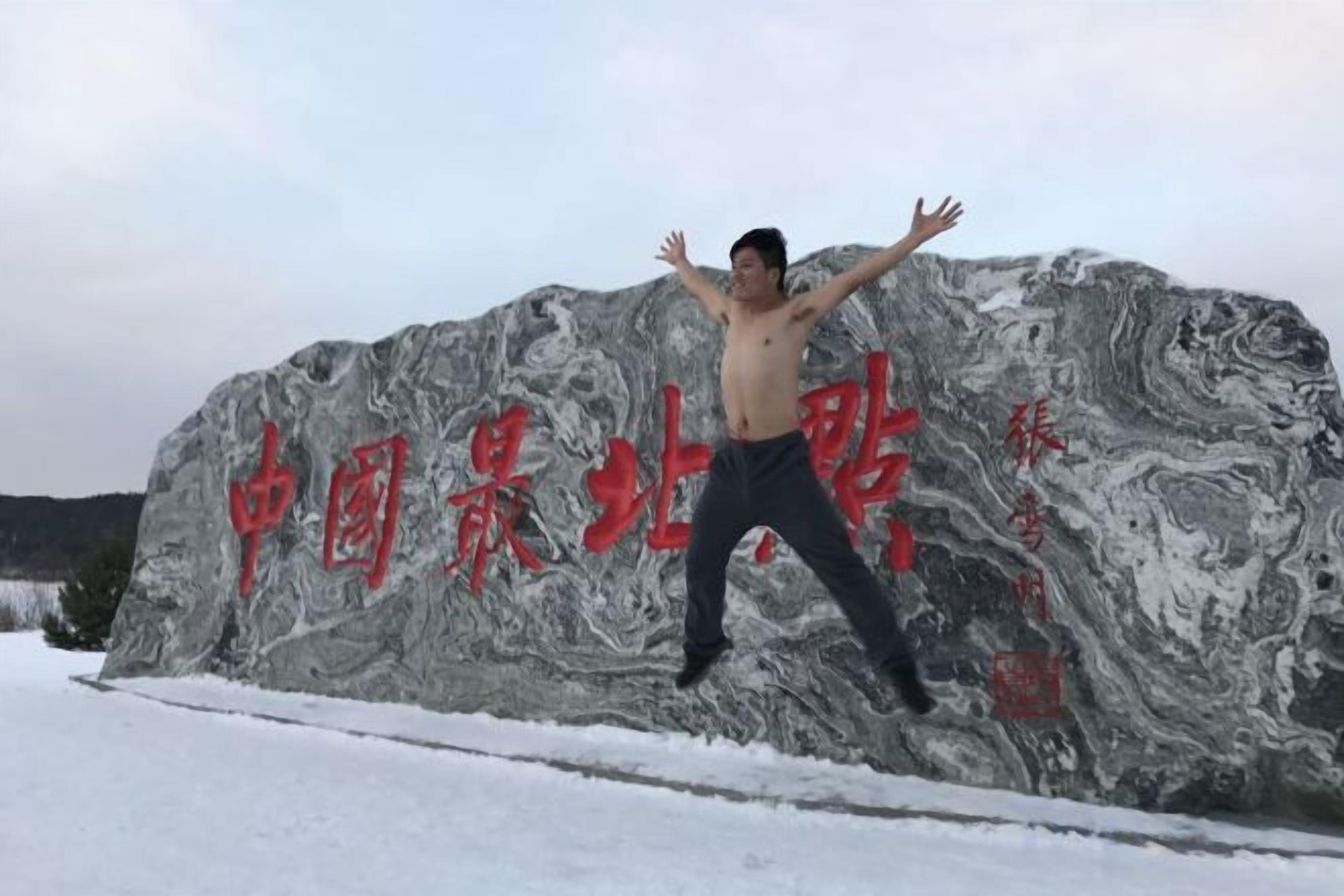 A person standing in front of a large rock with Chinese characters.