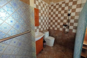 Un baño con pared de baldosas a cuadros, un inodoro blanco y una zona de ducha.