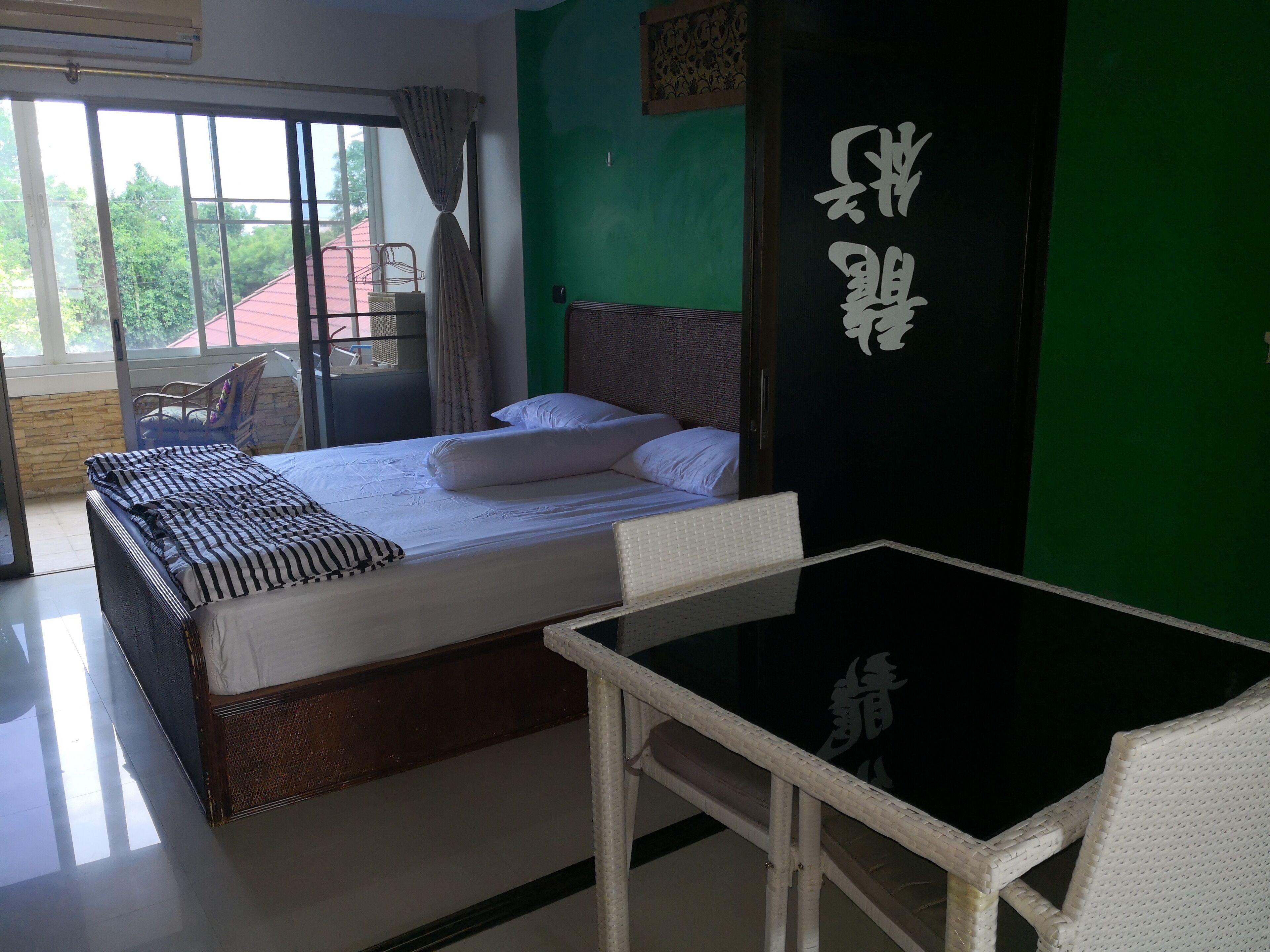 A hotel room with a bed, a chair, a table, and a view of the outside.
