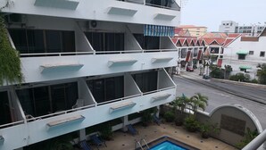 Un edificio de varios pisos con piscina, balcones con barandillas y plantas en macetas.