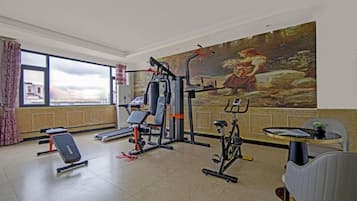 A gym with exercise equipment, a bench, and a mural on the wall.