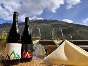 Two wine bottles, a glass of wine, and a napkin on a table with a mountain view in the background. - Hotel zum Lamm (Tarrenz)