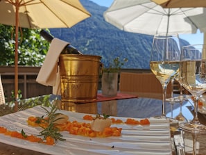 A table with a white plate of food, two glasses of white wine, and a gold bucket. - Hotel zum Lamm (Tarrenz)