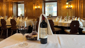 Uma sala de jantar com painéis de madeira, lustres e mesas postas para refeição.