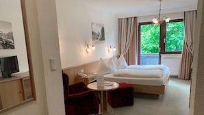 Quarto de hotel com uma cama, uma escrivaninha, uma cadeira e uma televisão.