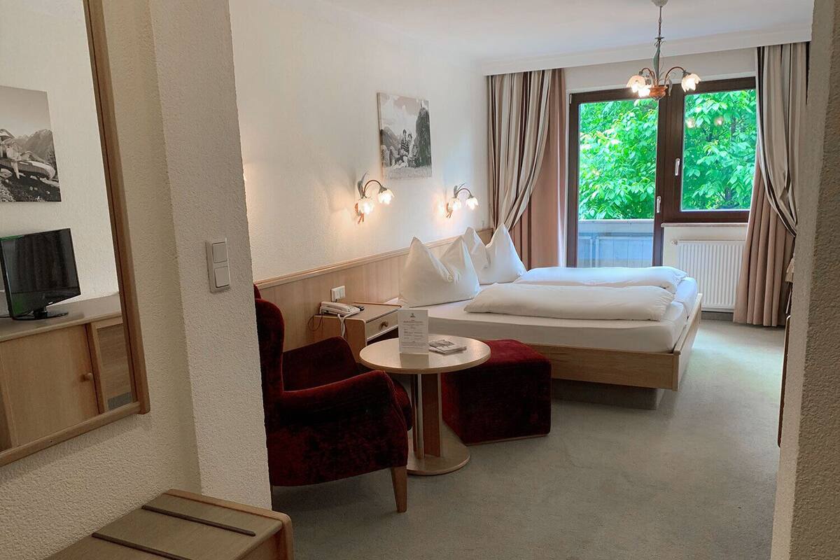 A hotel room with a bed, a desk, a chair, and a television.