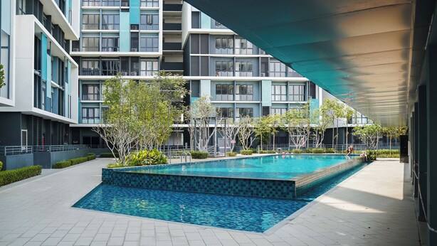 A modern building with a swimming pool, surrounded by greenery and a covered walkway. - KLIA AIRPORT HOMESTAY 5 (Sepang)